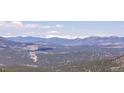Scenic view of rolling mountain peaks and lush green valleys with snow-capped peaks in the distance on a clear day at 6574 Olympus Dr, Evergreen, CO 80439