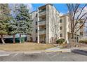 An angled view of the building's facade with balconies and lush green trees creating a peaceful living environment at 7780 W 38 Th Ave # 203, Wheat Ridge, CO 80033