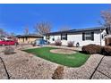 Quaint single-story home with solar panels, black shutters, and an easy-care gravel yard at 6060 Locust St, Commerce City, CO 80022