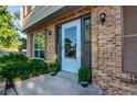 Close-up of front door with storm door, brick surround, and manicured bushes at 8538 W Glasgow Pl, Littleton, CO 80128