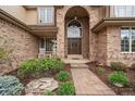 Charming brick home with a grand arched entrance, stone walkway, and well-maintained landscaping at 7914 S Clayton Cir, Centennial, CO 80122