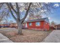 A single-story brick home with a large tree in the front yard, and a detached garage nearby at 1051 Lima St, Aurora, CO 80010