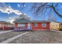 A cozy single-story brick home with a ramp, blue accents, and a well-maintained front yard on a sunny day at 1051 Lima St, Aurora, CO 80010