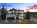 Charming two-story home with a well-maintained yard, three-car garage, and welcoming front porch at sunset at 1929 Baguette Dr, Castle Rock, CO 80108