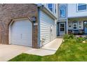 Garage with brick accent with home number, landscaped yard, and covered porch at 9155 W Portland Ave, Littleton, CO 80128