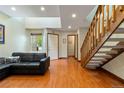 Sunlit living room featuring wood floors, a modern black couch, and open access to the staircase at 9155 W Portland Ave, Littleton, CO 80128