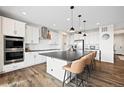 Bright kitchen with large island, stainless appliances, white cabinets, and hardwood flooring at 5088 S Quail St, Littleton, CO 80127