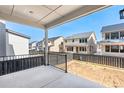 Covered patio with a black metal railing overlooking an unfinished backyard, with neighboring houses in the background at 8864 Moonshimmer Trl, Littleton, CO 80125