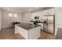 Modern kitchen boasts white cabinets, stainless steel appliances, a gray countertop island, and wood floors at 16432 Snowbourn Dr, Parker, CO 80134