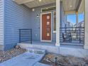 Inviting front porch with sleek black railings, concrete steps, and a modern red door at 3744 Celestial Ave, Castle Rock, CO 80109