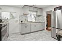 The kitchen has gray cabinets, stainless steel appliances, gray tile floors, and bright lighting at 1070 S Newton St, Denver, CO 80219