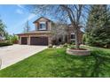 Beautiful two-story home featuring a three-car garage, stone accents, lush lawn, and mature trees at 9536 W Avalon Dr, Littleton, CO 80127