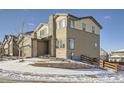 Two-story house with stone and siding exterior, snowy landscaping, and a wood fence at 14461 Mosaic Ave, Parker, CO 80134