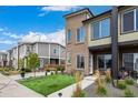 Modern townhome with a well-maintained front yard, green grass, and a contemporary design under a blue sky at 5371 E 63Rd Pl, Commerce City, CO 80022
