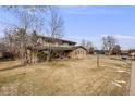 Traditional two-story home on large grassy lot with mature trees and blue sky at 6323 W Rowland Cir, Littleton, CO 80128