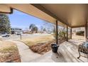 Cozy covered porch with classic black planter and seating, overlooking a quiet street at 6323 W Rowland Cir, Littleton, CO 80128