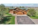 Aerial view of a log home with a green roof and long driveway nestled in a scenic, tree-filled landscape at 3557 Palmer Ridge Dr, Parker, CO 80134