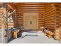 Inviting log home entrance featuring carved wooden doors, a bear carving, and comfortable seating at 3557 Palmer Ridge Dr, Parker, CO 80134