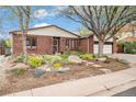 Beautiful brick home boasts a meticulously landscaped front yard with stepping stones and a lovely mature tree at 6235 W Floyd Ave, Denver, CO 80227