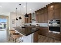 Modern kitchen featuring dark wood cabinets, stainless steel appliances, a center island, and designer pendant lights at 7202 Canyonpoint Rd, Castle Pines, CO 80108