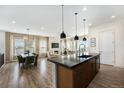 Open concept living space featuring a kitchen island, dining area, living room with fireplace, and abundant natural light at 7202 Canyonpoint Rd, Castle Pines, CO 80108