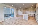 Open-concept living space with wood floors, sliding glass doors, and a view of the kitchen and staircase at 8635 Hotchkiss St, Littleton, CO 80125