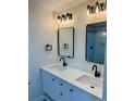 Bathroom featuring double vanity, black fixtures, modern light fixtures, and framed mirrors at 2320 S Valley Hwy, Denver, CO 80222