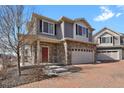 Charming two-story home with stone accents, a red front door, a brick driveway, and a well-maintained lawn at 26167 E Byers Pl, Aurora, CO 80018