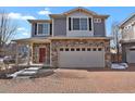 Stunning two-story home with a stone facade, a brick driveway, a red front door, and an attached two-car garage at 26167 E Byers Pl, Aurora, CO 80018