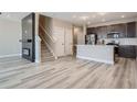 Open-concept space with a fireplace, staircase, and a modern kitchen with stainless steel appliances at 2443 W 69Th Pl, Denver, CO 80221