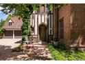 Elegant Tudor-style home with a brick exterior, a wooden front door, and lush greenery at 100 N Gaylord St, Denver, CO 80206