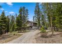 View of a two-story home with a deck surrounded by tall pine trees on a sunny day at 24 Ski Pole Ct, Breckenridge, CO 80424