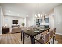 Open-concept dining area with modern chandelier, flowing to kitchen and living room at 21284 E 63Rd Dr, Aurora, CO 80019