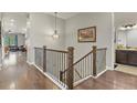 Well-lit hallway with hardwood floors, decorative railing, and view of the living room and bathroom at 21376 E Union Pl, Aurora, CO 80015