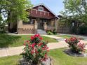 Charming brick home featuring a cozy front porch and a well-manicured lawn with vibrant rose bushes at 1418 Perry St, Denver, CO 80204