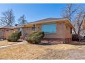 Charming single-story brick home with a large window and manicured landscaping at 3515 Grape St, Denver, CO 80207