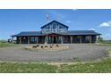 Beautiful front exterior of home with large windows, covered porch, manicured circular flower bed, and American flag at 3308 County Road 19, Fort Lupton, CO 80621