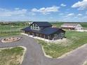 Stunning exterior shot of gray farmhouse, showcasing circular driveway, covered porch, and adjacent multi-bay garage at 3308 County Road 19, Fort Lupton, CO 80621