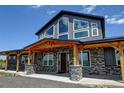 Eye-level exterior shot of the front entrance of the home, highlighting stone accents and beautiful wooden support beams at 3308 County Road 19, Fort Lupton, CO 80621