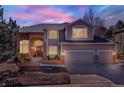 Charming two-story home showcasing brick and siding details under a twilight sky with illuminated interior at 7271 Brixham Cir, Castle Pines, CO 80108