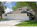 Angle view of charming home featuring mature trees, green lawn, and a spacious three-car garage at 6075 S Filbert Ct, Centennial, CO 80121