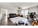 Bright living room with dark hardwood floors, ceiling fan, neutral paint, leather furniture and large windows at 1786 Quartz St, Castle Rock, CO 80109