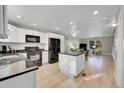 Bright kitchen featuring white cabinets, black appliances, granite countertops, and an island at 7360 E Princeton Ave, Denver, CO 80237