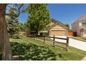 View of the exterior with a well-manicured lawn, rustic fence, and inviting driveway at 16102 Grebe Pl, Parker, CO 80134