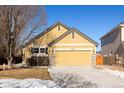 Exterior view of yellow home showcasing attached garage and driveway in front, with stone accents at 16102 Grebe Pl, Parker, CO 80134
