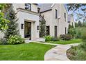 Charming home entrance with stone walkway, manicured lawn, and elegant black framed door at 27 Polo Club Cir, Denver, CO 80209