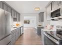 Well-lit kitchen with gray cabinetry, stainless steel appliances, and a view into an adjacent sun-lit living space at 306 N 14Th Ave, Brighton, CO 80601