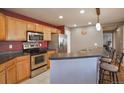 The kitchen features stainless steel appliances, light wood cabinets, and a bar area with seating at 11844 Oak Hill Way # A, Commerce City, CO 80640