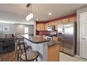 This kitchen features stainless steel appliances, wooden cabinets, bar seating and a red accent wall at 11844 Oak Hill Way # A, Commerce City, CO 80640