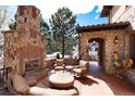 Inviting stone patio with fireplace, comfortable seating, and serene outdoor ambiance at 8002 Galileo Way, Littleton, CO 80125